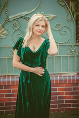 Obraz premium A middle-aged woman in a vintage green velvet dress and emerald accessories for a walk in a small cottage town. The concept of vintage and retro femininity