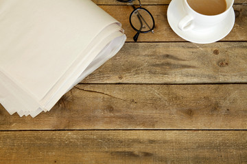 Newspaper with eyeglasses on wooden table