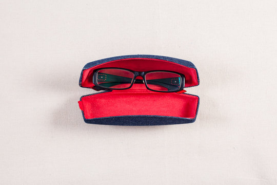 Eyeglass And Red Boxed On Fabric Background.