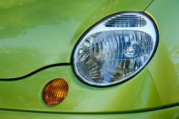 Part of car: headlamp and turn signal on green car.