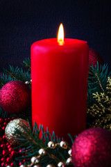 Christmas decoration burning candles spruce branches, Christmas balls on a dark background with copy space, festive mood and atmosphere