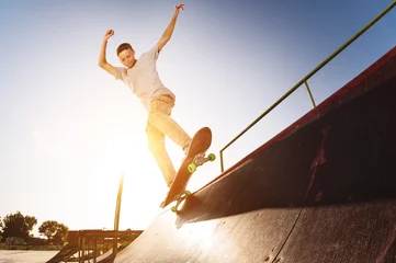 Fotobehang Teen skater hang up over a ramp on a skateboard in a skate park © yanik88