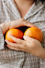 Woman holding two ripe oranges in her hands.