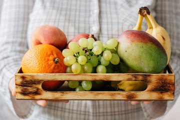 Woman holding box with fruits in hands.