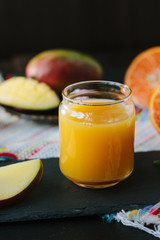Mango and orange detox juice over black slate board.