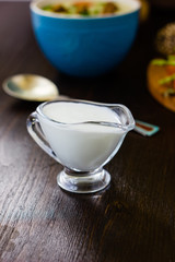 Natural cream dip in a glass bowl on dark wooden board.