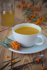 Tea with sea-buckthorn orange berries in a cup and organic honey