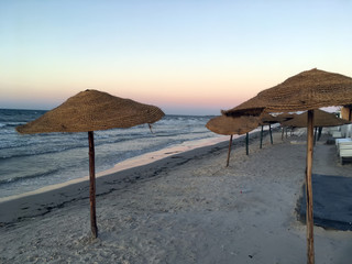 Берег Средиземного моря - пляж, песок, плетеные зонтики, закат
