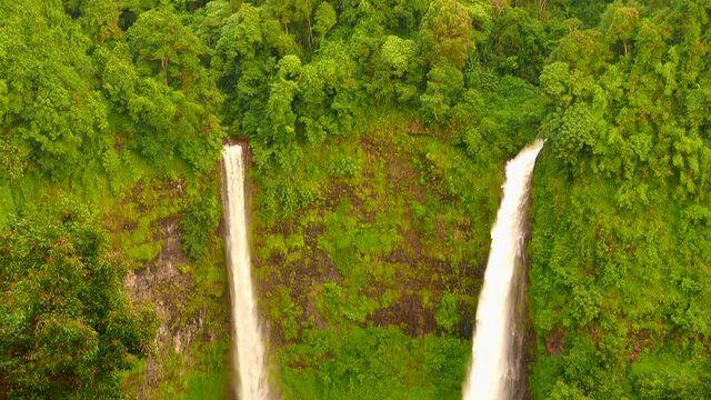 Waterfall in reverse. Water flowing up a twin waterfall in a tropical jungle. 