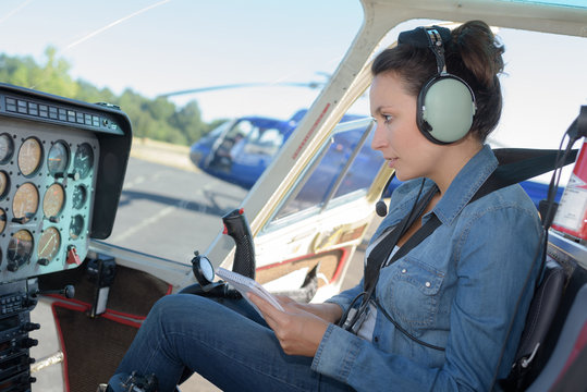female helicopter pilot reading a manual while sitting in cockpit
