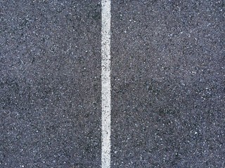 Abstract white lines painted on distressed asphalt concrete surface