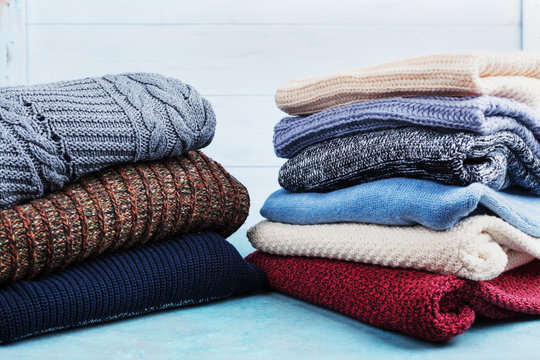 Colorful Wool Sweaters And Knitted Winter Clothes On Blue Wooden Background.