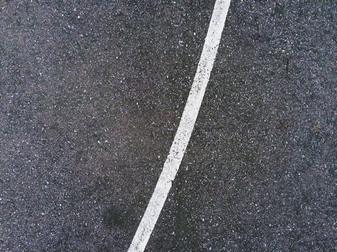 Abstract white lines painted on distressed asphalt concrete surface