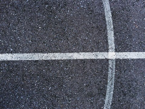 Abstract white lines painted on distressed asphalt concrete surface