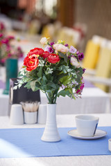 Bouquet of artificial flowers is decorated on the table in a cafe near the beach. Kemer, Turkey
