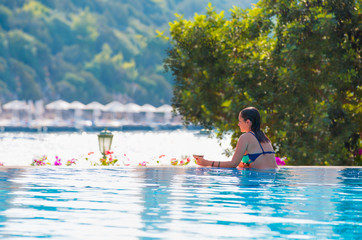 Beautiful girl rests near the swimming pool