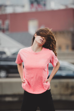 Carefree woman dancing on roof, holding t-shirt suggestively