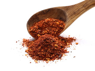 pile crushed red cayenne pepper, dried chili flakes, seeds and wooden spoon isolated on white background