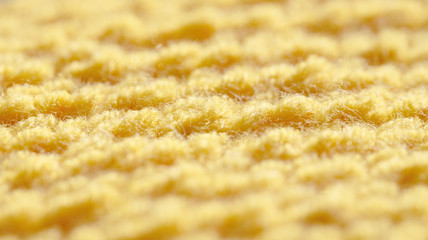The texture of the knitted fabric is yellow. Background with woolen threads.
