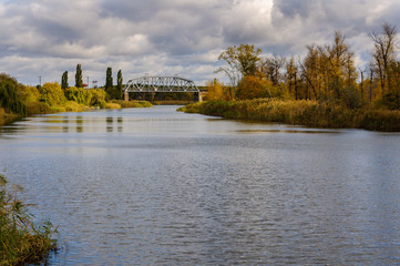 Obraz premium Railway bridge over the river against the background of autumn forest