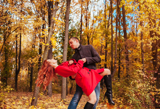 Young couple dances in autumn forest among colorful trees