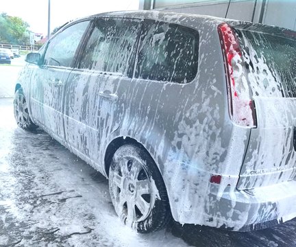 mycie auta na myjni samoobsługowej bezdotykowej, samoch&oacute;d pokryty pianą, widok na samoch&oacute;d z boku, 