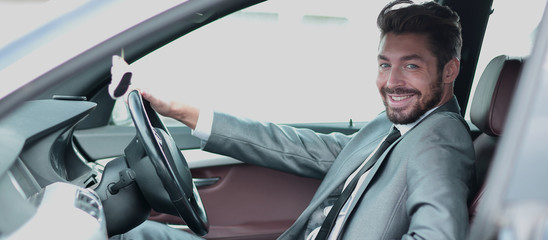Portrait of an handsome smiling business man driving his car