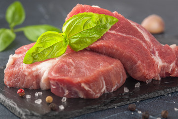 pork meat with pepper and garlic on a black background