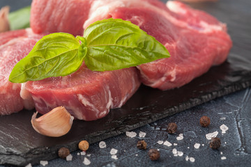 pork meat with pepper and garlic on a black background