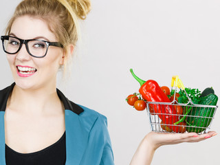 Woman holds shopping basket with vegetables