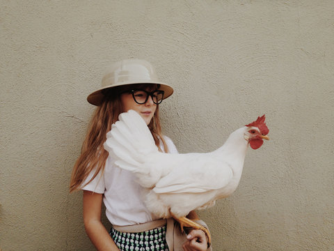 young girl wearing safari hat holding a chicken