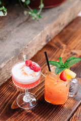 Two alcoholic cocktails garnished with berries and mint