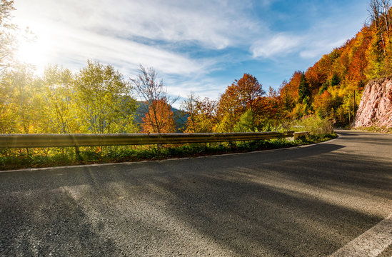 asphalt road through autumn forest in mountains. beautiful and colorful scenery on sunny day under the blue sky with some clouds