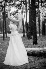 Fototapeta na wymiar Romantic tender bride in a white dress in the forest. The concept of a wedding in a rustic style. Beauty of the bride in combination with forest and nature, wedding fashion and dress elements
