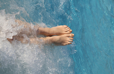 barefoot feet of a young woman during the whirlpool in the pool