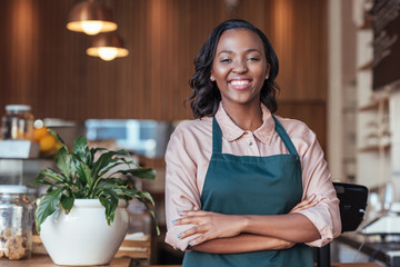 Smiling African entrepreneur standing at the counter of her cafe