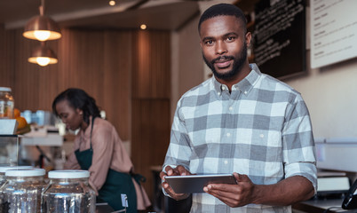 Young African entrepreneur working at the counter of his cafe