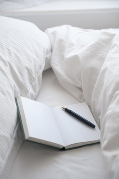 open book with fountain pen on an unmade bed