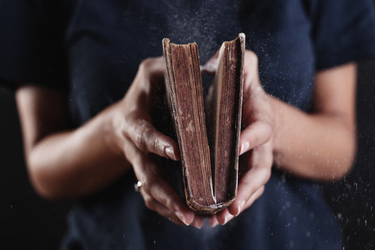 Hands of a woman opened a dusty old book.