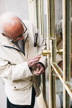 Elderly man opening the door of house.