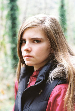 somber teenager in vest looking at camera