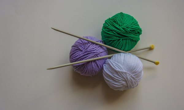 Drei Kn&auml;ul Wolle mit Stricknadeln