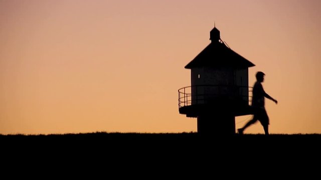 Mann geht auf Deich am Leuchtturm vorbei spazieren, HD Video