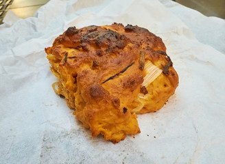 Typical pizzi leccesi bread, also called puccia or pucce salentine in a streetfood presentation, on a rustic paper. In this recipe with tomato and onion, Puglia, Italy.
