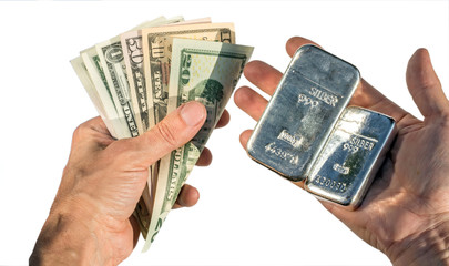 Silver bullion and dollar bills in the hands isolated on white.