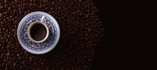 traditional hot coffee cup with beans  over a black background.
