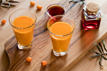Two glasses of sea buckthorn juice, with sea buckthorn oil and berries