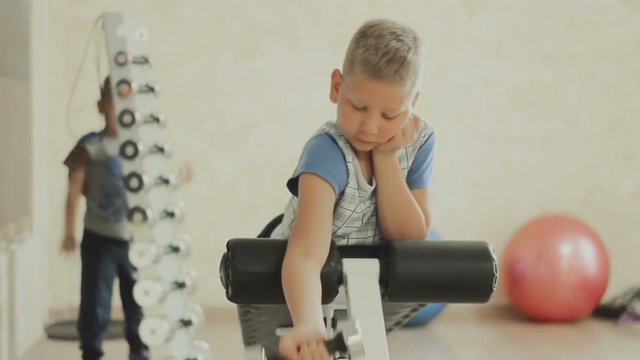 Smiling teenager doing heavy dumbbell exercise for biceps. Boy working out with dumbbells on training apparatus. Strength and motivation. The concept of a healthy lifestyle. GYM