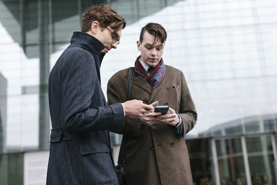 Two Businessmen Checking Messages on Cell Phone