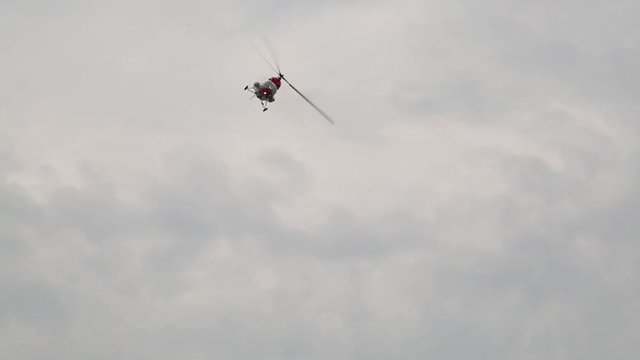 The helicopter performs aerobatics figures in the sky. Shooting from the ground.